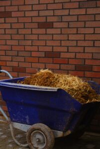 Blue wheelbarrow filled with hay against a brick wall in Eskişehir, Turkey.